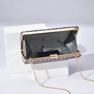 Elegant metallic frame evening clutch bag featuring fine chain strap and secure lock detail.