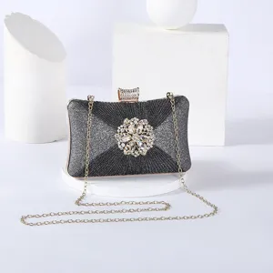 Detailed shot of sparkling black evening clutch with rhinestone floral clasp and gold chain.