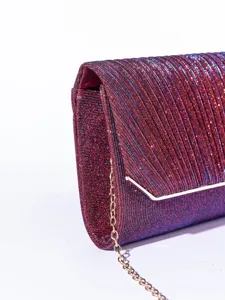 Close-up detail of glittering evening clutch bag with fine pleated texture and metal chain.