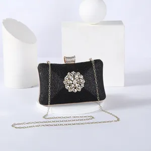Elegant black glitter evening clutch with sparkling rhinestone flower brooch and gold chain.