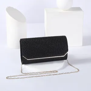 Elegant black glitter evening clutch with gold edge trim and fine chain strap detail.