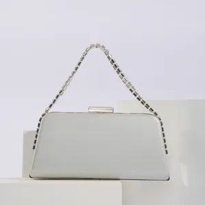 Close-up detail of silver evening clutch bag featuring sparkling rhinestone chain handle design.