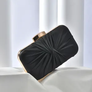 Black satin ruched evening clutch bag detail showing exquisite gold metal frame and elegant folds.