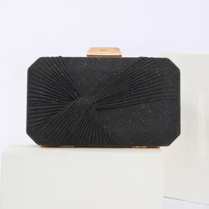 Close-up view of black glitter pleated evening clutch bag with gold metallic lock detail.