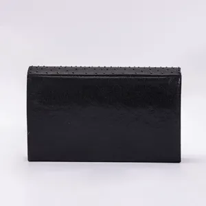 Detailed view of the black evening clutch bag featuring delicate studded texture flap.