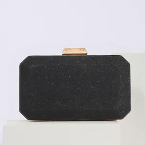 Elegant black glitter evening clutch bag detail view with gold-tone metal clasp lock.
