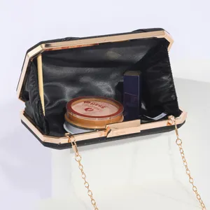 Detailed view of black glitter evening clutch bag with gold metal frame and chain.