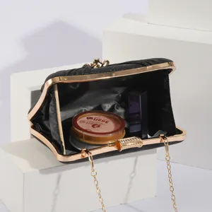 Détail de pochette de soirée noire pailletée, avec fermoir fleur en strass et chaîne dorée.