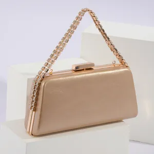 Detailed view of luxury gold evening clutch bag with sparkling rhinestone chain handle.