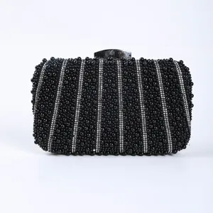 Detailed close-up shot of black beaded evening clutch with rhinestone stripes and metal clasp.