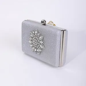 Silver glitter evening clutch bag with crystal flower decoration and metal clasp details.