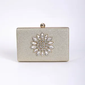 Rhinestone evening clutch bag detail, gold glitter surface with crystal flower decoration.