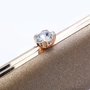 Elegant women's golden glitter evening clutch bag with sparkling crystal flower clasp.