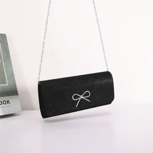 Black glitter evening bag with rhinestone bow and silver chain shoulder strap for parties.