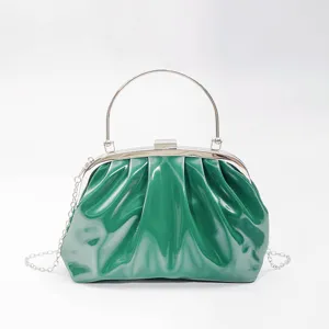 Green glossy pleated clutch bag close-up, metal frame kiss-lock evening bag details style.