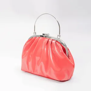 Coral red patent leather ruched evening handbag detail, showing the glossy texture and metal frame.