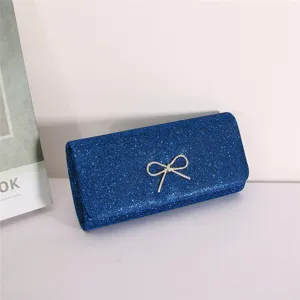 Blue glitter evening clutch bag close-up detail showcasing sparkling rhinestone bow decoration.