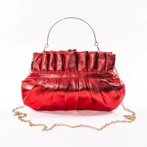 Red metallic ruched clutch bag detail showing shiny leather texture and golden metal handle.