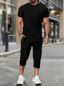 Close-up detail of casual black short-sleeve t-shirt and cargo shorts outfit worn by model.