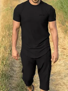Detail view of the black short sleeve t-shirt and casual pants outfit in outdoor setting.