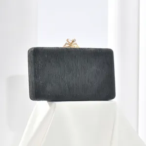 Black evening clutch bag detail view, shimmering texture design with crystal diamond clasp.