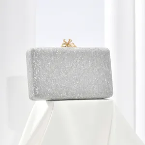 Elegant silver glitter evening clutch bag with sparkling crystal bow clasp for formal party events.