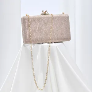 Elegant evening clutch detail showing sparkling champagne fabric, gold chain, and crystal clasp.