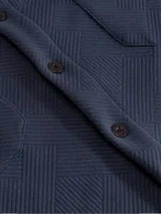 Gros plan sur la texture du tissu jacquard et les details des boutons de la chemise homme.