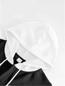 Vue rapprochée du col du sweat à capuche bicolore noir et blanc et du tissu texturé.