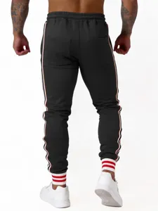 Detailgezicht op casual herensportbroek met stijlvolle zijstrepen en geribbelde boorden.
