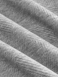 Détail du tissu de chemise pour homme montrant une douce texture jacquard grise tissée.
