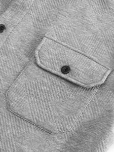 Détail de poche de chemise pour homme, tissu texturé gris avec design de bouton noir.