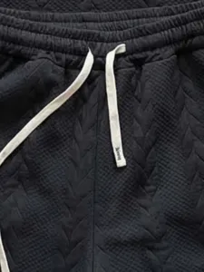 Men's black knit jacquard shorts detail shot with contrast drawstring streetwear style.