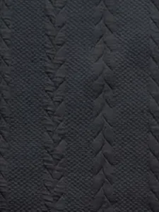 Close-up detail shot of dark grey knit fabric with classic cable pattern and vertical stripes.