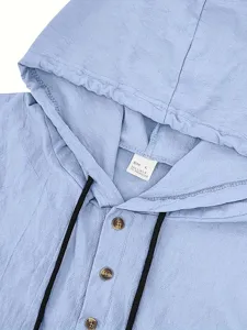 Close-up of men's linen hooded shirt detail, showing textured fabric, drawstring, and buttons.