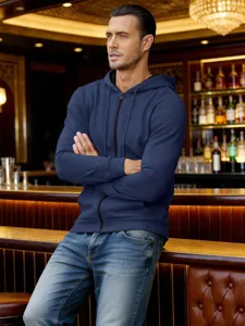 Vue détaillée du sweat à capuche zippé bleu foncé pour homme dans un bar élégant.