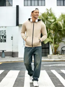 Détail de rue extérieure montrant un sweat à capuche beige zippé pour homme stylé.