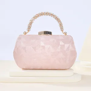 Detalle de bolso de noche con asa de estrases rosa, textura de satin y cierre metalico.