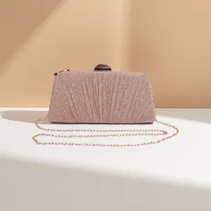 Close-up of pink glitter evening clutch showing pleated design and metallic chain strap details.