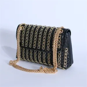 Close-up detail of luxury black rhinestone evening shoulder bag with gold chain strap.