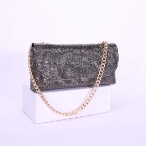 Close-up view of a sparkling rhinestone evening clutch bag with elegant gold chain strap detail.