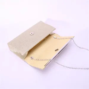 Detail view of a glamorous gold glitter evening clutch bag with detachable metal chain strap.