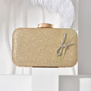 Close-up of the elegant gold glitter evening clutch featuring sparkling crystal bow and tassel.