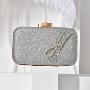 Elegant silver glitter evening clutch bag featuring a dazzling rhinestone knot detail and gold clasp.