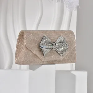 Chic champagne glitter evening clutch with sparkling rhinestone bow detail for parties.