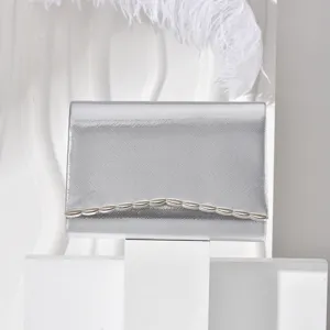 Silver evening clutch bag with metallic wave detail, elegant envelope shoulder bag for women.
