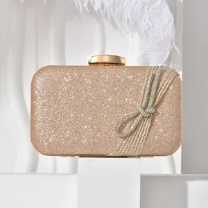 Elegant glitter evening clutch bag featuring a dazzling rhinestone bow and gold hardware.