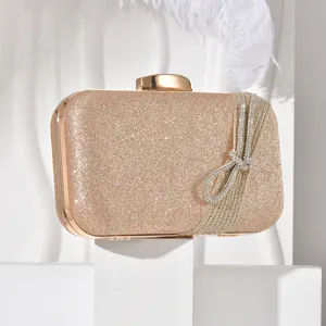Gold glitter evening clutch bag with sparkling rhinestone bow detail, elegant piece.
