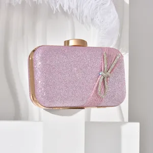 Pink glitter evening clutch with gold metal frame and sparkling rhinestone bow detail.