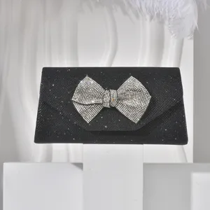 Exquisite black glitter evening clutch featuring a dazzling crystal bow, detailed close-up shot.